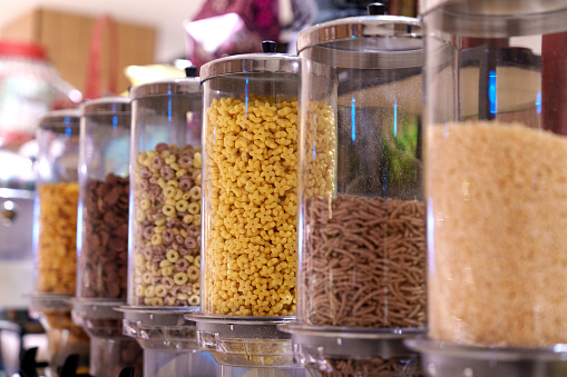 Dispensers filled with cereals arranged in a zero waste grocery store. These dispensers are arranged to promote sustainable living and reduce consumerism.