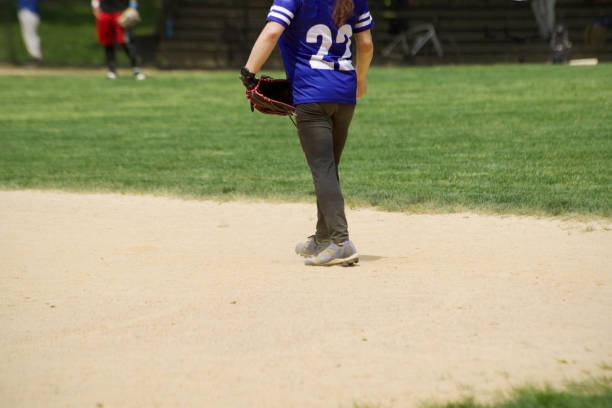 istock baseball field with a female player in a summer game in central park, ny 1495551264