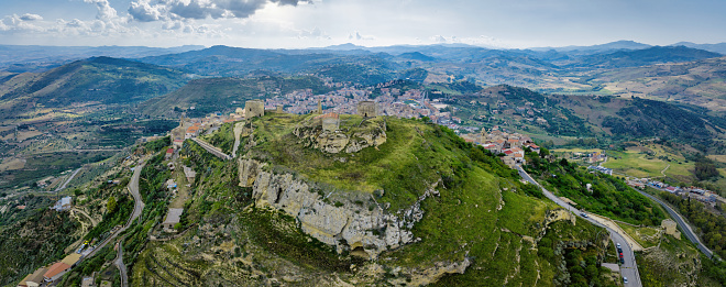 Agira, Sicily, Italy - May 27, 2023: Agira Castle Ruins on Top of conical shaped Mount Teja 820m above sea level. Aerial Drone point of view over the central Sicilian Hinterland, natural landscape and rural nature. Remains of the Castello di Agira - ancient greek - roman - byzantine fort on top of the Mount Teja Hill. Agira, Enna Province, Sicily Island, Italy, Southern Europe, Europe