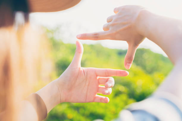 istock Hand making frame gesture with looking on the tree brunch in spring garden background, concept of creativity and imagination. 1495552870