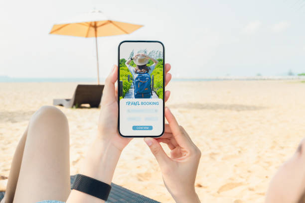 istock Woman sitting on deckchair on the beach using smartphone with application booking flight travel search ticket holiday and hotel on website, concept technology online marketing and promotion. 1495553252