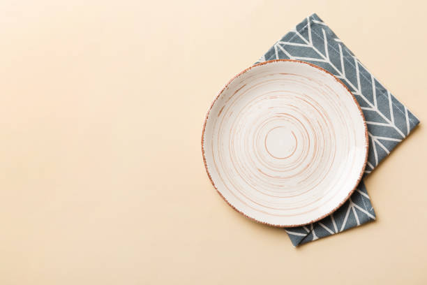 istock Top view on colored background empty round white plate on tablecloth for food. Empty dish on napkin with space for your design 1495565162