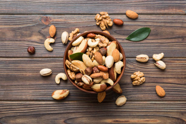 istock mixed nuts in bowl. Mix of various nuts on colored background. pistachios, cashews, walnuts, hazelnuts, peanuts and brazil nuts 1495565176