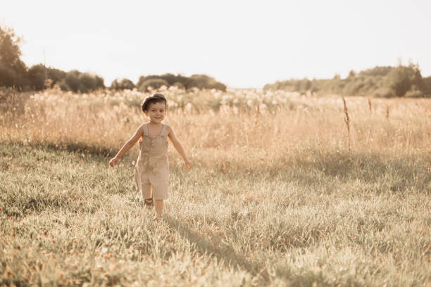 The boy-child is having fun and actively running in the field. A cheerful and sincerely rejoicing boy. Childhood in the countryside.