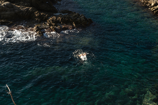 A person jumping in the Balearic Sea in summer.