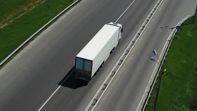 Trucks drive along the highway on a sunny day. Aerial Follow Shot.