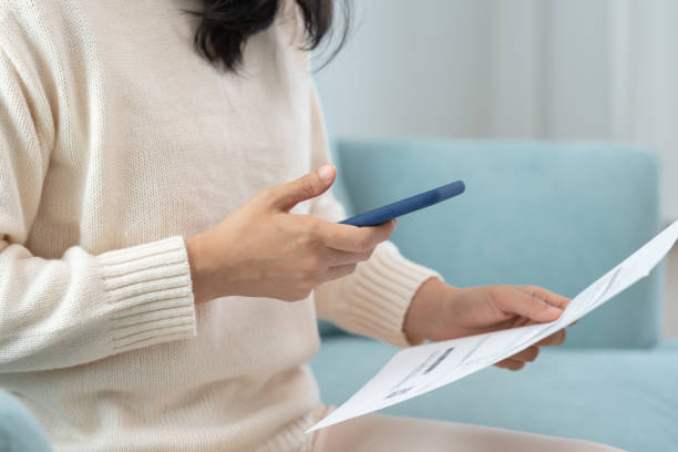 istock Modern woman use phone to scan barcode or QR codes to pay credit card bill after receive document invoice. payment, receive, paying electricity, digital payments without money, technology, scanning 1495579270