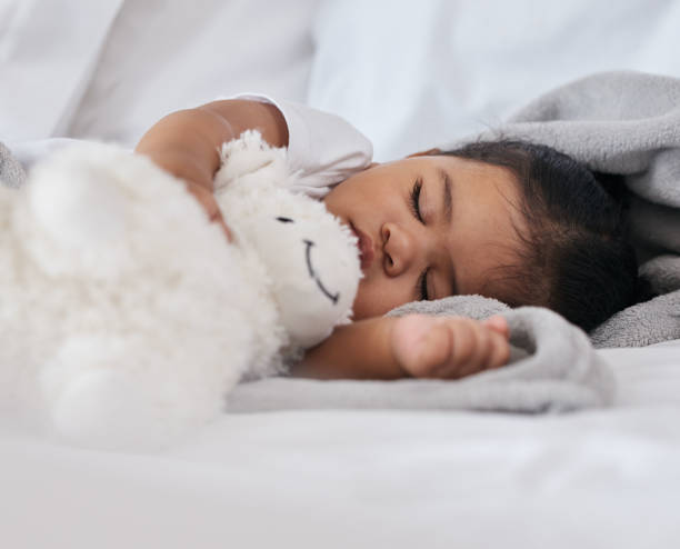 istock Sleeping, teddy bear and cute with baby in bedroom for relax, comfortable and dreaming. Innocence, young and rest with tired child at home for and napping with toy for bedtime, youth and sweet 1495579574