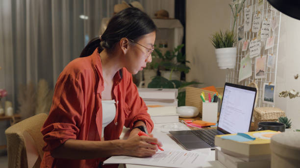 istock Young Asian woman wear casual sit front of desk with computer laptop and think create on work idea in living room at house at night. Work from home. 1495581921