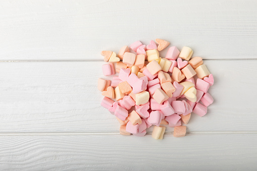 Loose fruit marshmallows on white texture wood.Sweets and snacks for a snack.Chewy candy close-up.Copy space.Place for text.