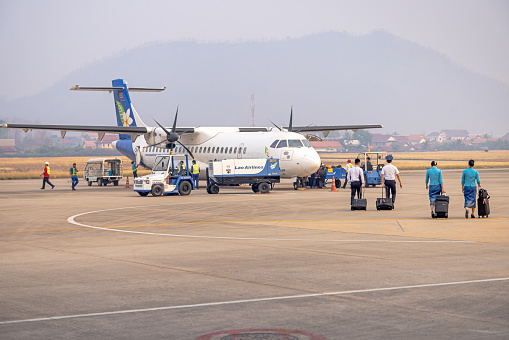 Luang Prabang Airport, Luang Prabang, Laos - March 22th 2023: Airplane staff walking to an ATR72-600 from Lao Airlines in front of the runway at the airport in the former capital of Laos