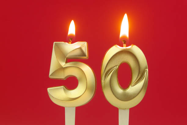 Gold birthday candles burning on red. Number 50 stock photo