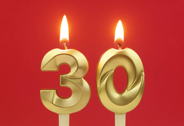 istock Gold birthday candles burning on red. Number 30. 1495586038