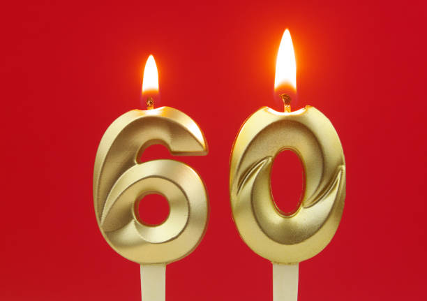 istock Gold birthday candles burning on red. Number 60. 1495586045