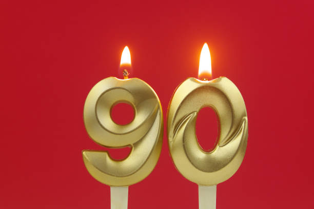 istock Gold birthday candles burning on red. Number 90. 1495586058