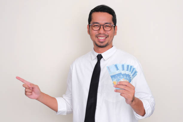 istock Asian man showing excited expression when looking and pointing to money that he hold 1495586162