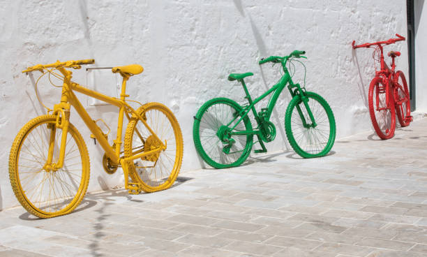 istock Three bicycles painted yellow green and red - primary colours - resting against a bright white wall 1495587370