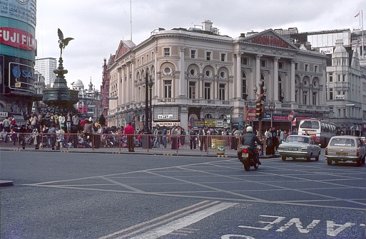 London, England, UK, 1978. City life with Londoners, tourists, buildings and street traffic at famous Piccadilly Circus in London.