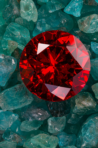 Red ruby diamond diamond on placed on a pile of raw sky blue gemstones.\njewelry are lovely present for valentine day\ncolorful raw stone background.lived a life of luxury.