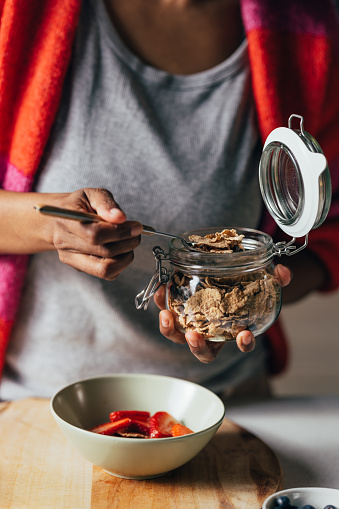 Morning routine: A close up view of an unrecognizable African-American female making a vegetarian meal with strawberries and a few spoons of cereals.