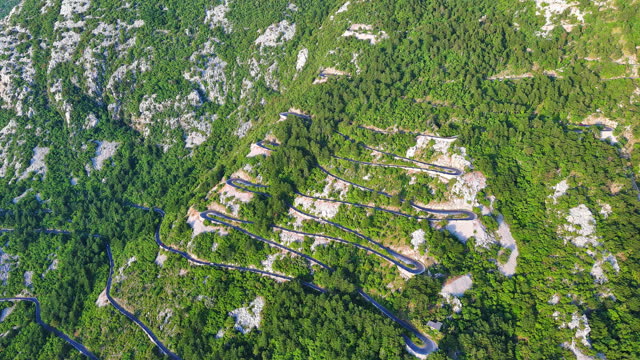 Winding road - Lovcensky serpentine with dangerous turns that leads to the top of the Montenegrin mountains covered with vegetation