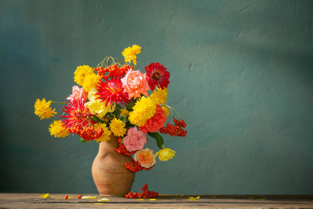 red and yellow flowers on jug in sunlight on background dark wall