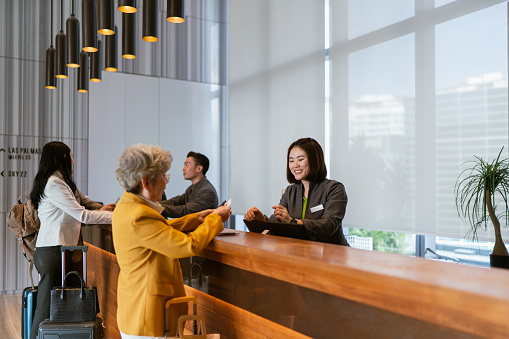 Business travel - Asian business professionals on corporate trip checking into a hotel
