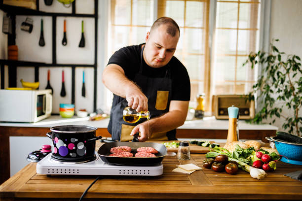 istock Overweight man adding cooking oil on electrical barbecue 1495603623