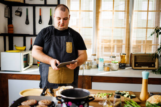 istock Overweight man looking recipe on digital tablet 1495604333