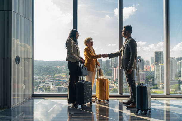 Traveling senior Chinese businesswoman shaking hands with another business executive at the hotel stock photo