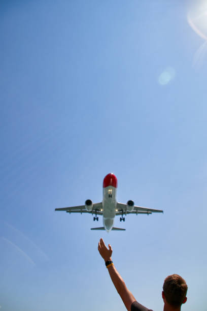 istock a man waves to a low flying plane that flies over his head 1495618294