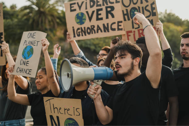 istock Group of diverse protesters with placards with globe illustrations and megaphone shouting with raised arms during demonstration 1495620971