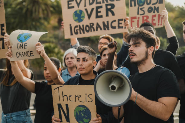 istock Group of multiethnic protesters with placards and man with loudspeaker representing ecological problem during demonstration on street 1495621044