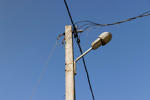 High-voltage power lines mounted on concrete poles, metal wires on poles against a blue sky background