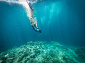 Young Man Snorkeling and Diving Downwards To Coral Reef