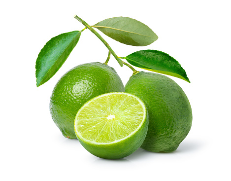 Fresh limes with green leaves on branch and cut in half sliced isolated on white background.