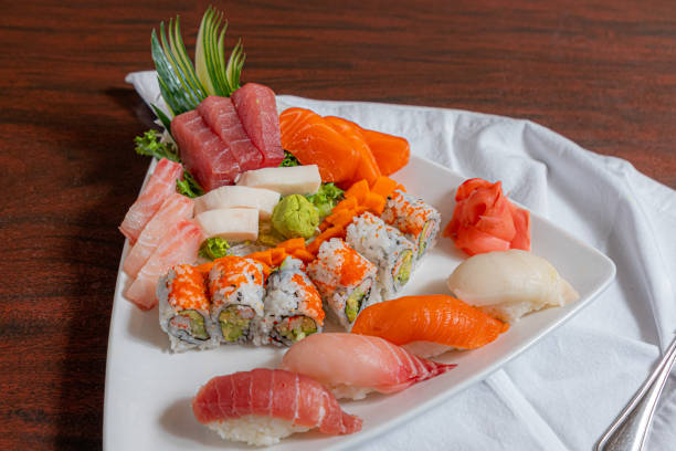 A set of rolls of different kinds with wasabi, red marinated imbere and sushi sticks, isolated on a black background. Top views