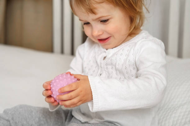 linda niña jugando bolas táctiles nudosas. la mano del niño pequeño juega a la pelota de masaje sensorial. mejorar el proceso cognitivo y físico. desarrollo del cerebro. apoyo para niños con tdah, autismo, inquietud - child sensory perception expressing negativity human hand fotografías e imágenes de stock