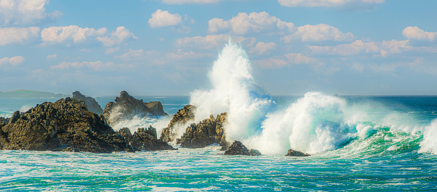 Large turbulent ocean waves crashing on shore rocks, off California Coast, after a pacific coast storm.