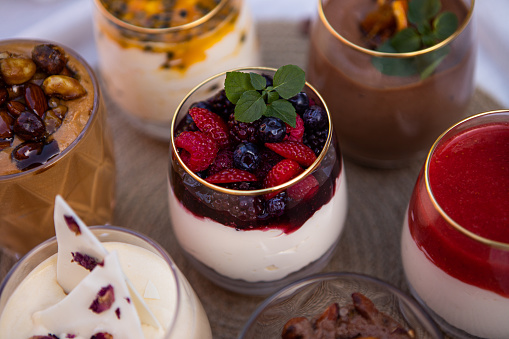 Delicious passion fruit cheescake, strawberry and red fruits berries cheescakes, black chocolate mousse, white chocolate mousse and dulce de leche mousse served in a glass cup - Argentine culture - Buenos Aires - Argentina