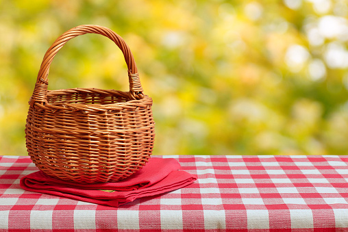 Empty wicker basket on a red checkered tablecloth. Autumn background. Free space for collage