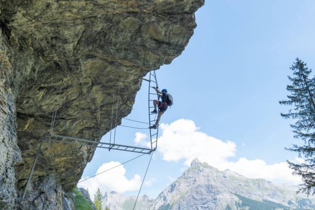 istock Low angle view, man on Via Ferrata climbing up a ladder, success concept 1495646680