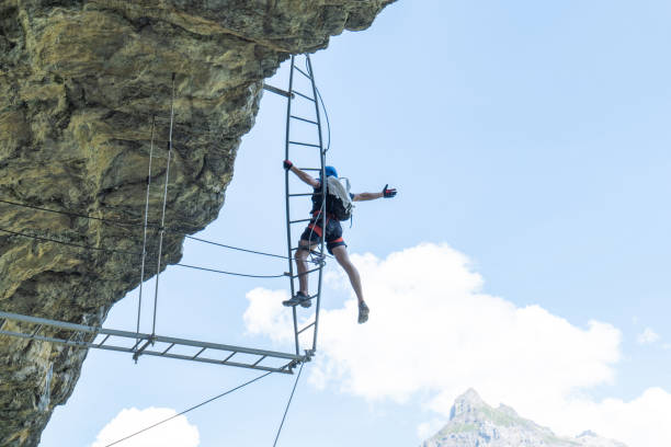 istock Low angle view, man on Via Ferrata climbing up a ladder, success concept 1495646751