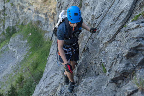 istock Young man on Via Ferrata climbing up a ladder on a rock face 1495648382