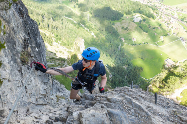 istock Young man on Via Ferrata climbing up a ladder on a rock face 1495651517