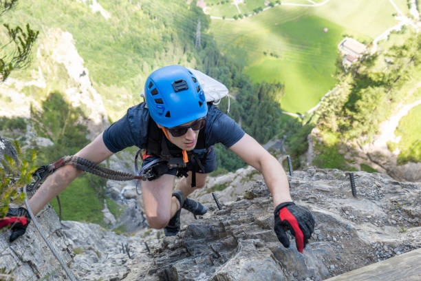istock Young man on Via Ferrata climbing up a ladder on a rock face 1495651590