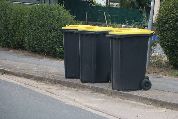 istock three dark plastic garbage cans with a yellow lid and plastic garbage are on the street ready for collection for recycling 1495663211