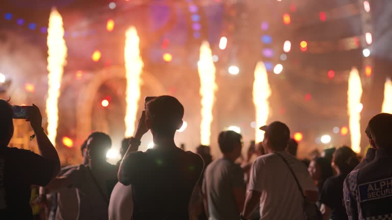 Crowd dancing and cheering at a festival concert while glitter is falling from above.