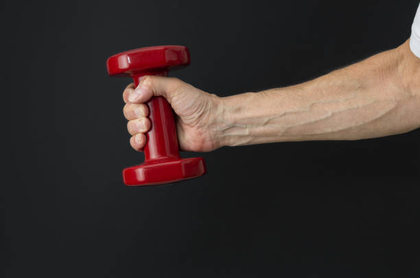 istock Man's hand with dumbbell close up on a black background 1495663816