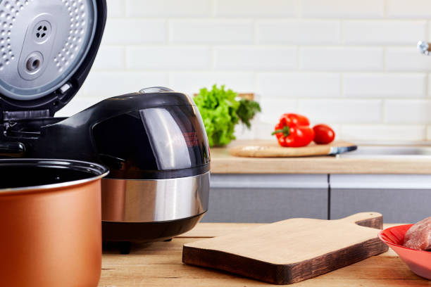 istock Cutting board with vegetables and multicooker on table in modern kitchen. Electric crockpot and food at home kitchen. Automatic slo-cooker. 1495663940